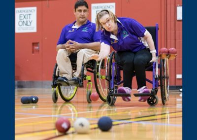 A female boccia players rolls the ball during a game as another player watches on.
