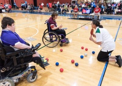 An umpire guides two athletes competing to win in a game of Boccia.