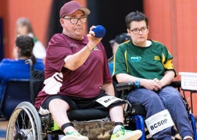 A male boccia player aiming to throw the ball during a competition.