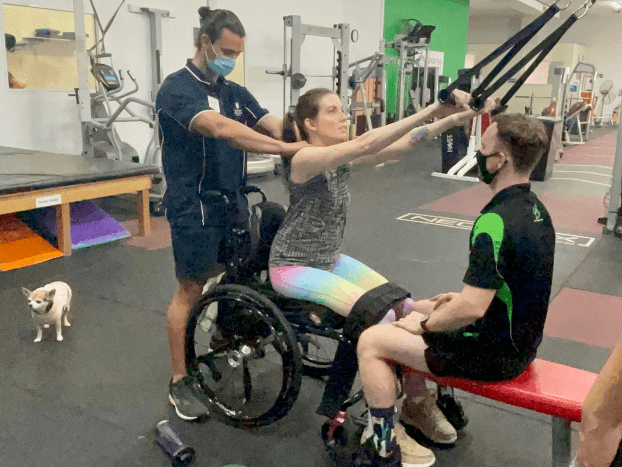 With the help of trainers, a young female client completes exercise physiology on a treadmill.