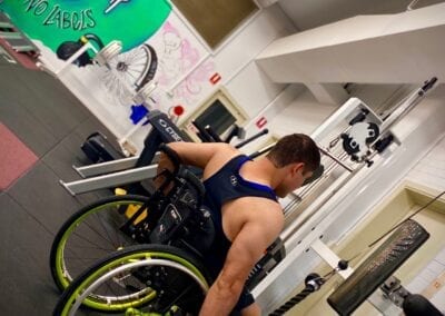 Sporting Wheelies male client uses weights for fitness building at Brisbane gym.