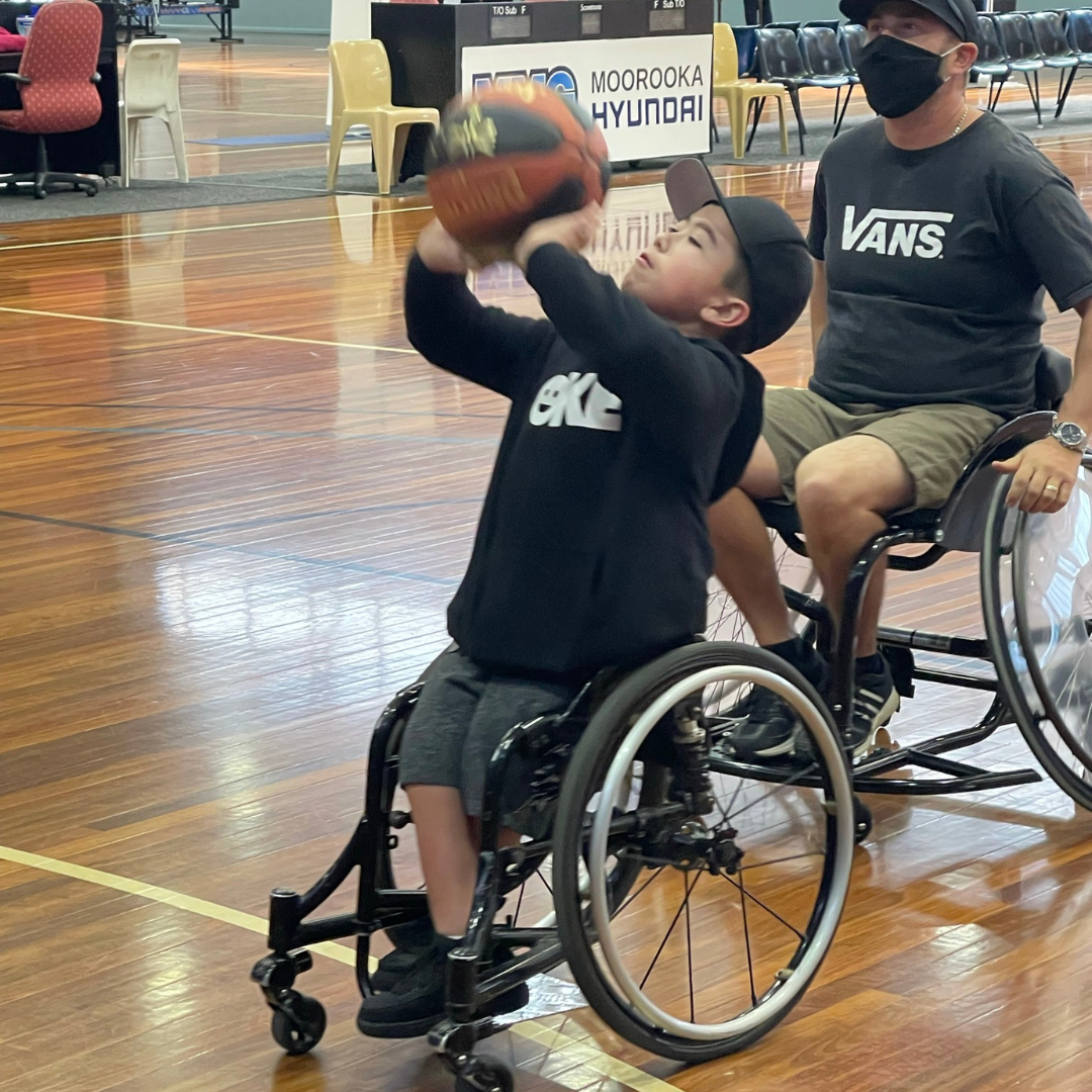 A young girl plays wheelchair basketball on the court.