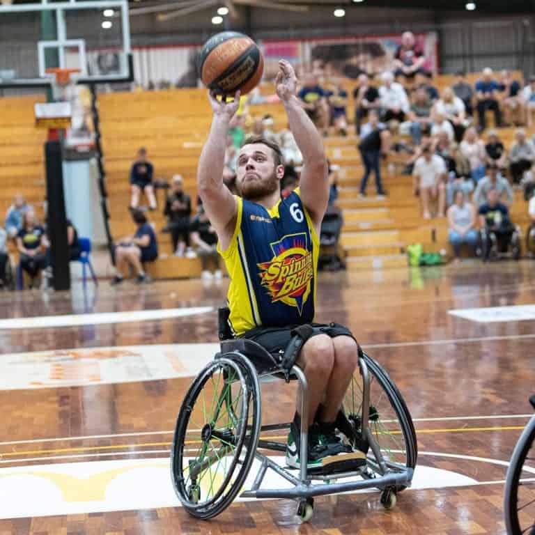 Male para athlete aims to shoot the ball in a competitive game of wheelchair basketball.