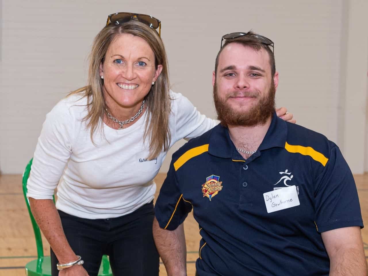 A man in a wheelchair and woman pose together for a photo at the Sporting Wheelies Brisbane gym.