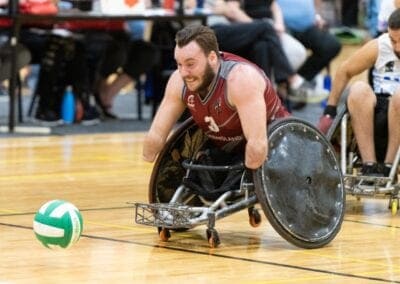 A male para athlete races after the ball in a game of Wheelchair rugby.