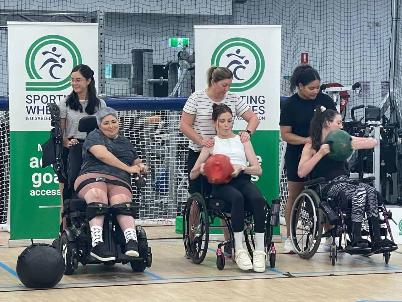 Female sporting wheelies clients using weights at a group fitness class.