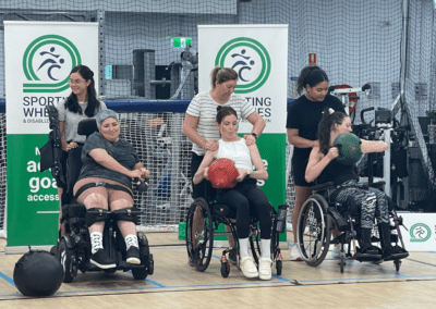 Female sporting wheelies clients using weights at a group fitness class.