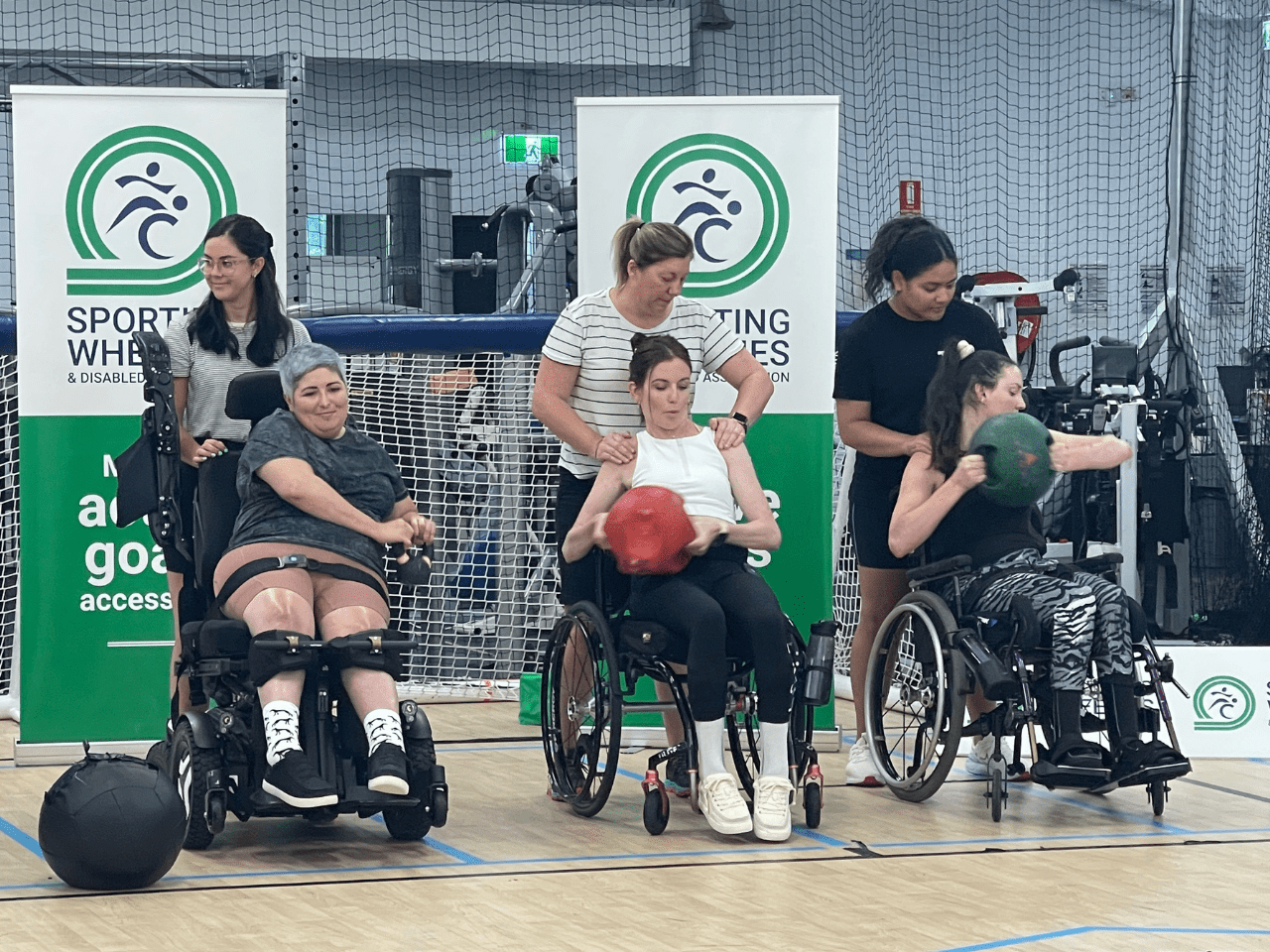 Female sporting wheelies clients using weights at a group fitness class.