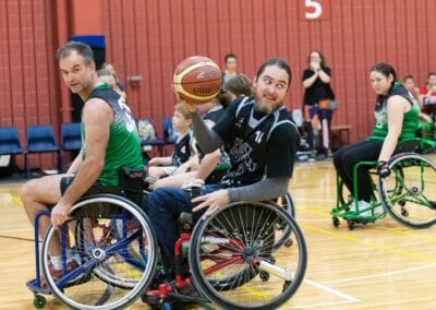 Wheelchair basketball player rolls past opponents to pass the ball during a game.