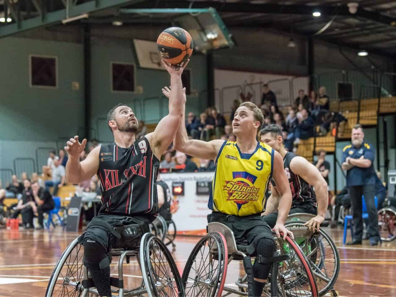 Two players compete for possession of the ball during a game of wheelchair basketball.