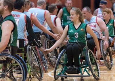 Two teams shake hands with each other after a game of wheelchair basketball.