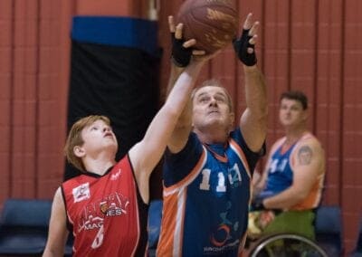 A young male athlete attempts to defend the ball during a game of wheelchair basketball.