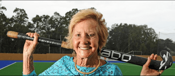 A woman poses with her hockey stick on the field.