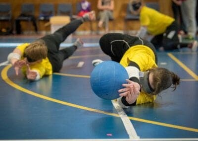 A female athlete makes a dive for the ball during a competitive match of Goalball.