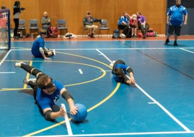 Goalball team members dive across the court to defend a ball coming towards them.