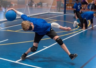 A Goalball male athlete prepares to throw the ball across the court.