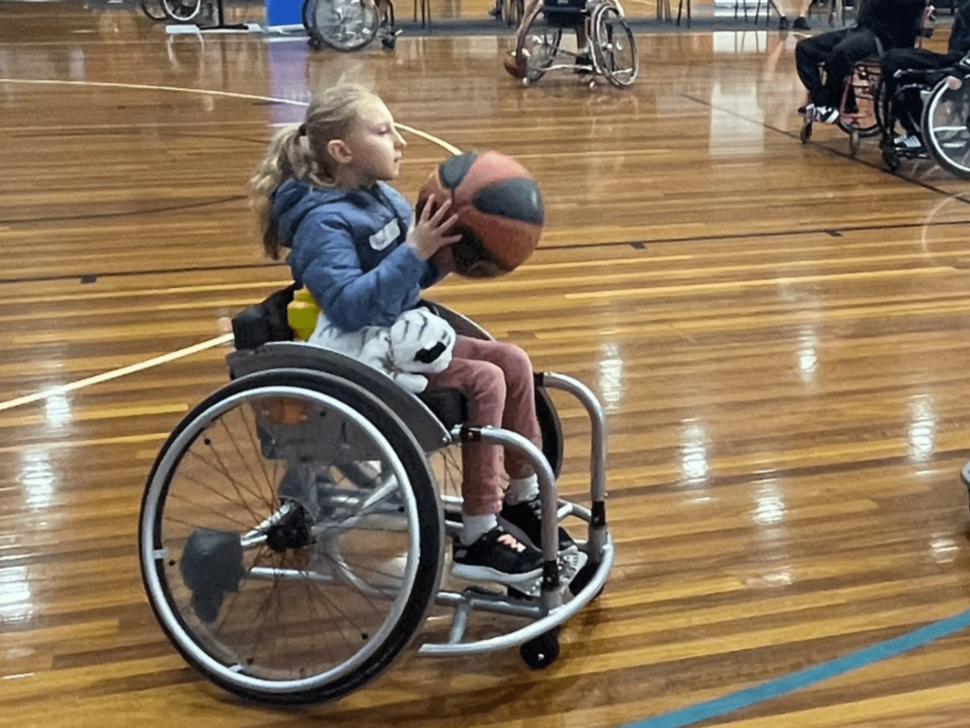 A young girl plays wheelchair basketball on the court.