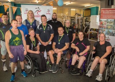 Various athletes come together for a group photo following a power lifting competition.